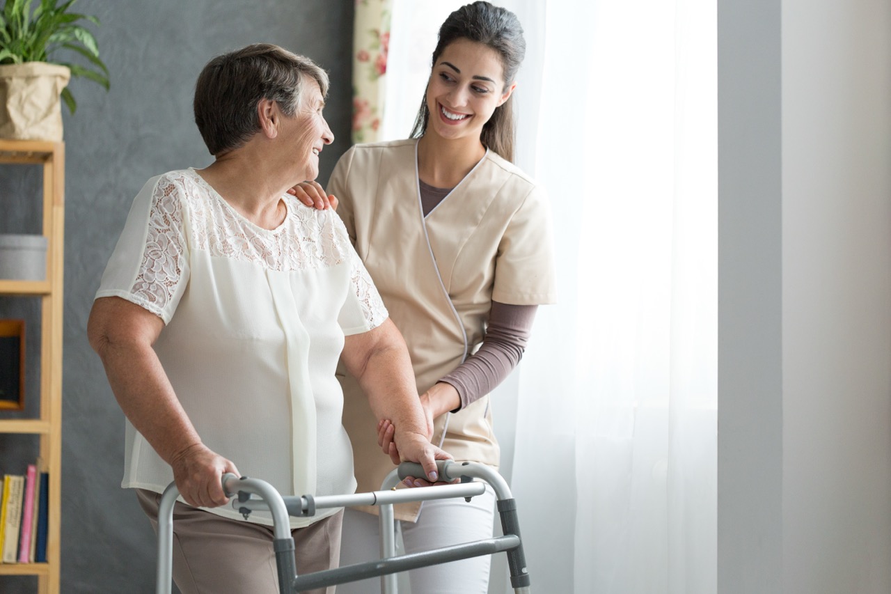 After a hip replacement, a woman is guided by a healthcare professional. 