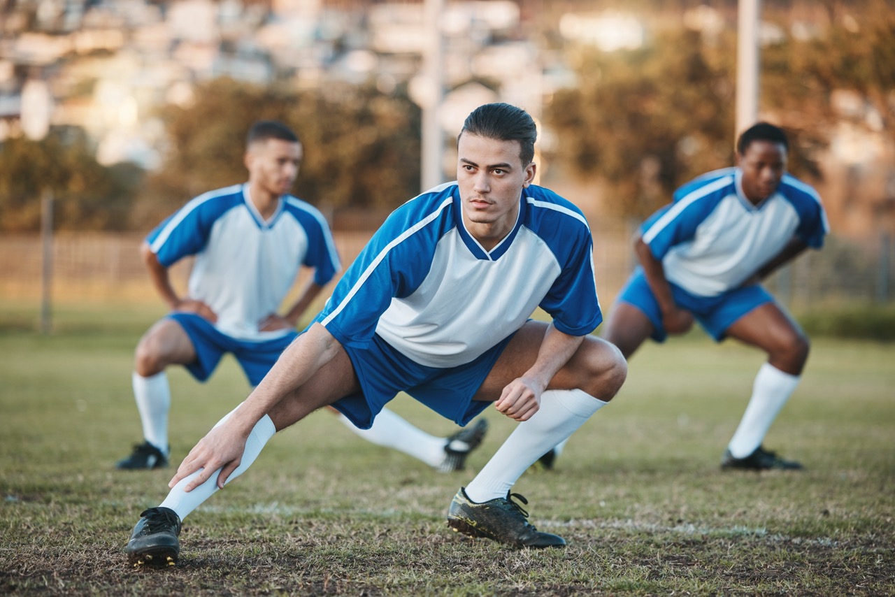 Male soccer players doing pregame team stretching on the field. 