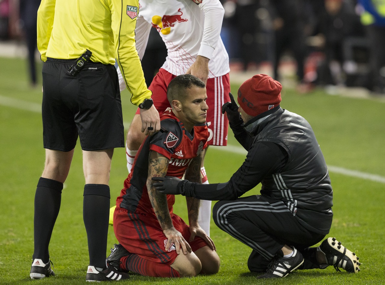 An athlete’s vision being evaluated on the field by a coach after injury. 